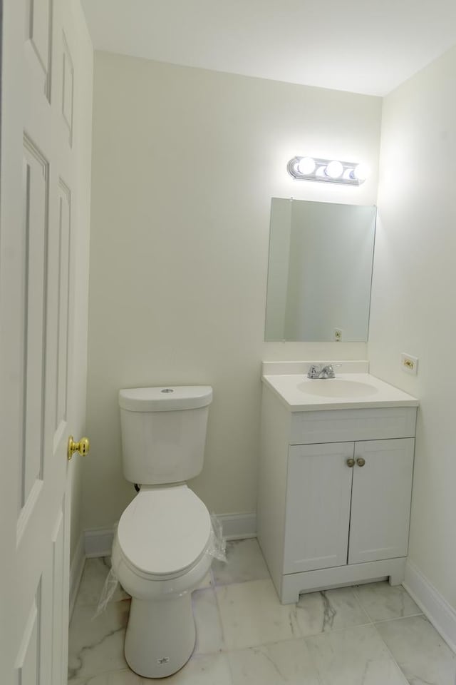 bathroom featuring toilet, marble finish floor, vanity, and baseboards