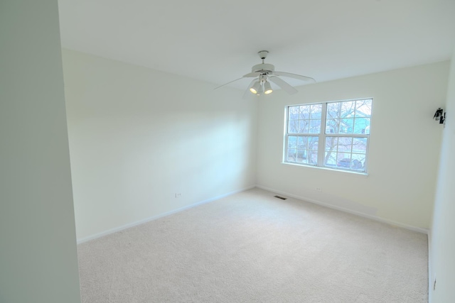 empty room featuring carpet flooring, ceiling fan, visible vents, and baseboards