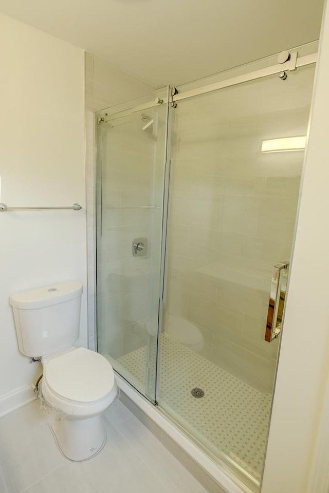 full bathroom with toilet, a shower stall, and tile patterned floors