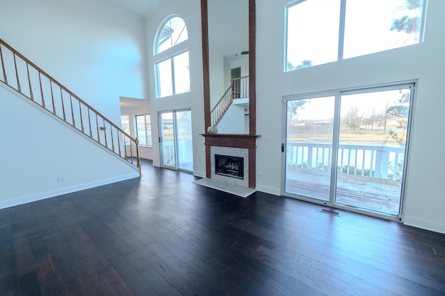 unfurnished living room featuring a fireplace with flush hearth, visible vents, baseboards, stairs, and dark wood finished floors