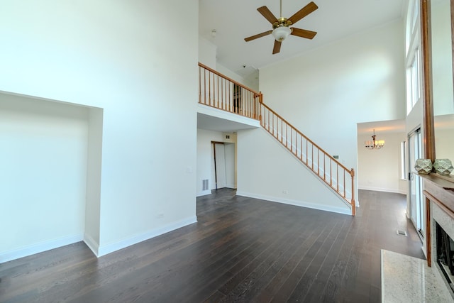 unfurnished living room with dark wood-style floors, stairway, a high ceiling, a fireplace with flush hearth, and baseboards