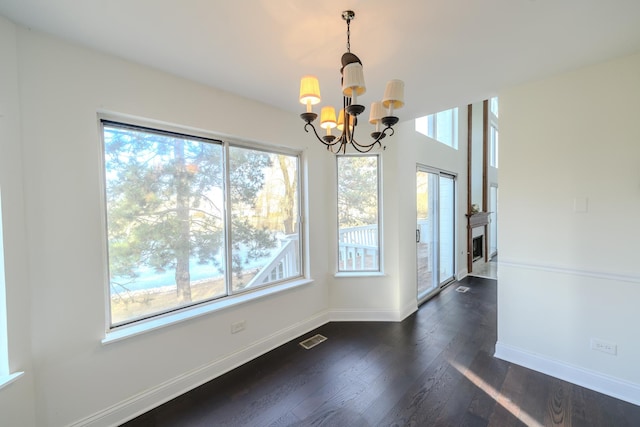 unfurnished dining area featuring dark wood-style floors, plenty of natural light, visible vents, and baseboards