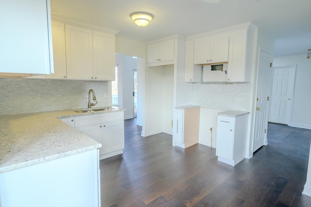 kitchen with white cabinets, light stone countertops, dark wood-style flooring, and a sink