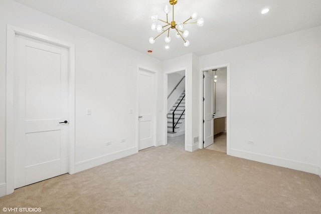 empty room featuring a chandelier, carpet, stairway, and baseboards