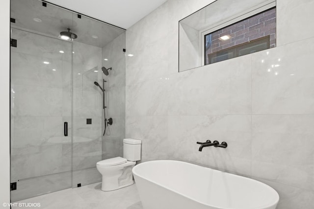 full bathroom with toilet, a freestanding tub, a shower stall, and tile walls