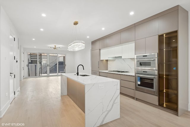 kitchen featuring modern cabinets, a sink, gas stovetop, and light wood-style floors