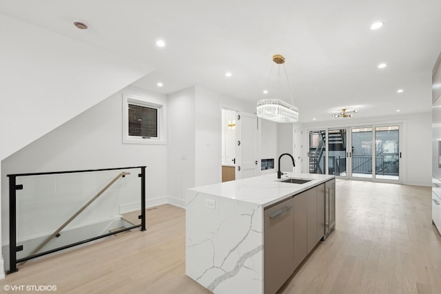 kitchen with light wood finished floors, recessed lighting, a kitchen island with sink, a sink, and modern cabinets