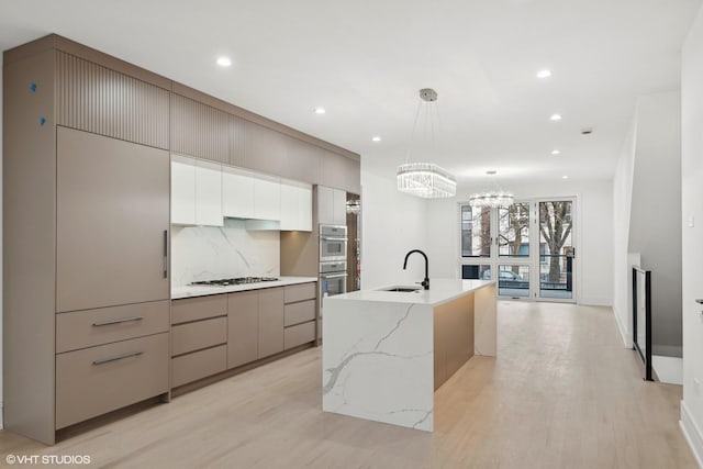 kitchen featuring gas stovetop, modern cabinets, backsplash, and a sink