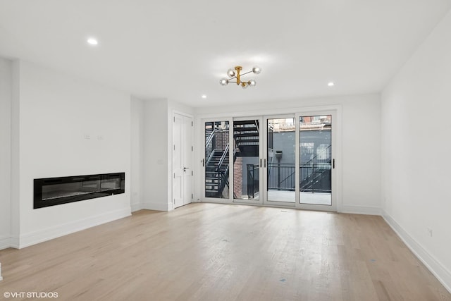 unfurnished living room featuring wood finished floors, recessed lighting, a glass covered fireplace, and baseboards