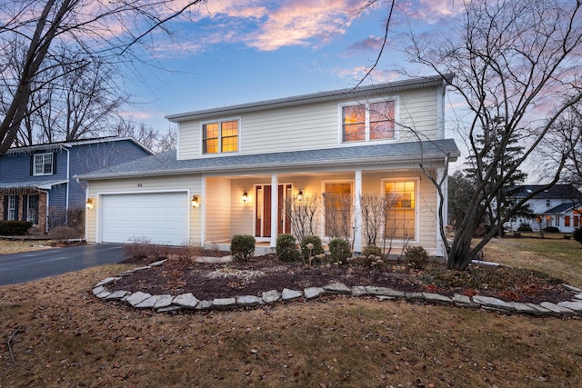 traditional-style house featuring a garage, covered porch, and driveway