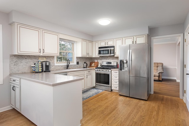 kitchen featuring stainless steel appliances, light wood-type flooring, a peninsula, and decorative backsplash