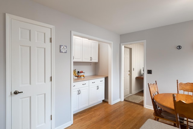 kitchen with light wood-style floors, baseboards, white cabinetry, and light countertops