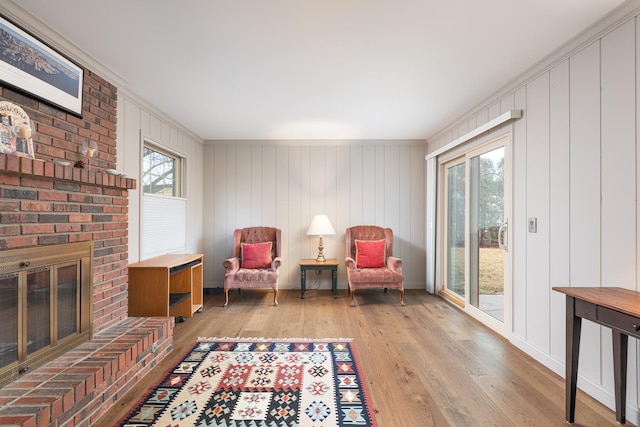 living area with baseboards, light wood-type flooring, a fireplace, and crown molding