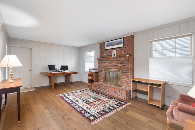 office area with a fireplace, wood finished floors, and crown molding