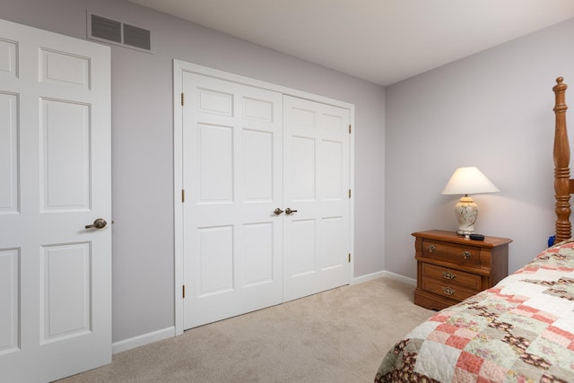 bedroom with baseboards, a closet, visible vents, and light colored carpet