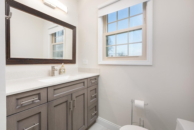 half bathroom with vanity, toilet, and baseboards