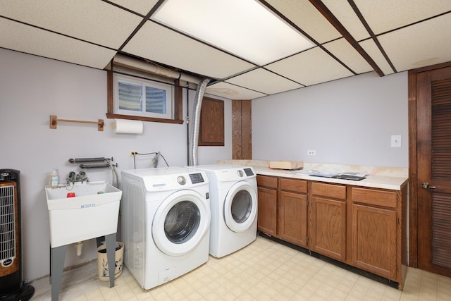 washroom featuring a sink, light floors, washer and clothes dryer, and cabinet space