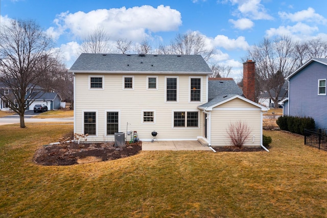 rear view of property featuring a patio, a yard, a chimney, and roof with shingles