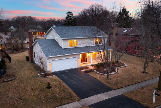 traditional home featuring driveway, a lawn, a chimney, roof with shingles, and an attached garage