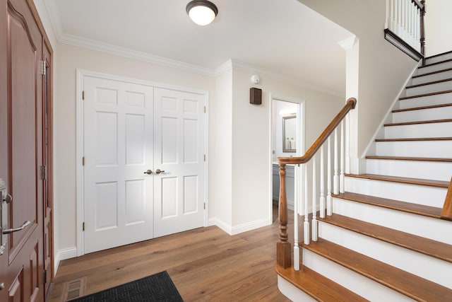 entryway with baseboards, stairway, wood finished floors, and crown molding