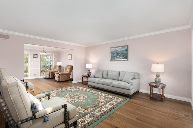 living room featuring visible vents, crown molding, baseboards, and wood finished floors