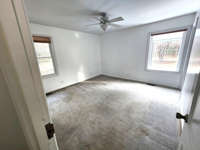 spare room with a wealth of natural light, carpet flooring, visible vents, and baseboards