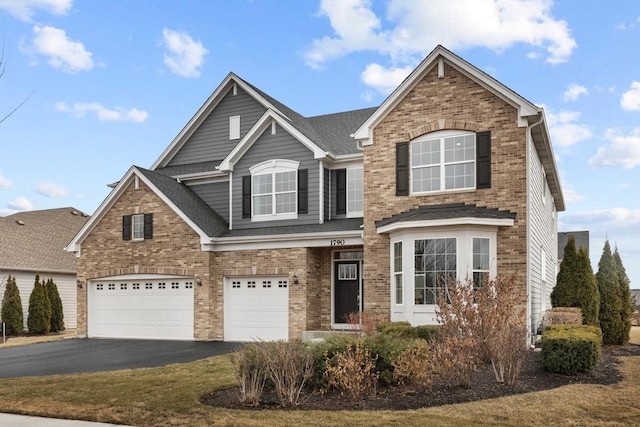 traditional-style house with a garage, a shingled roof, aphalt driveway, and brick siding