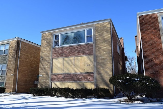 snow covered property with brick siding