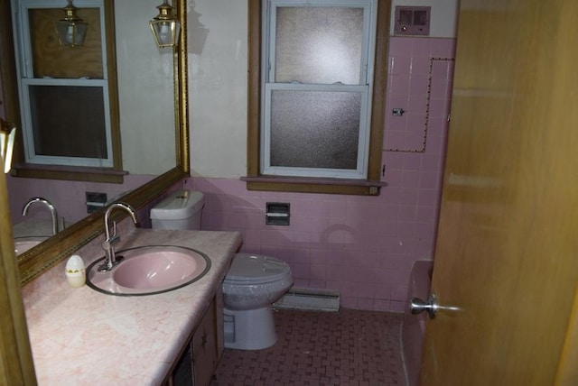 bathroom featuring toilet, a baseboard radiator, tile patterned floors, vanity, and tile walls