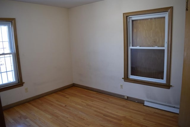 spare room featuring a baseboard radiator, light wood-style flooring, and baseboards