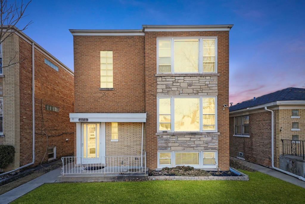 2630 N 73rd Ct, Elmwood Park, IL 60707 - front of property at dusk featuring stone siding, a lawn, and brick siding