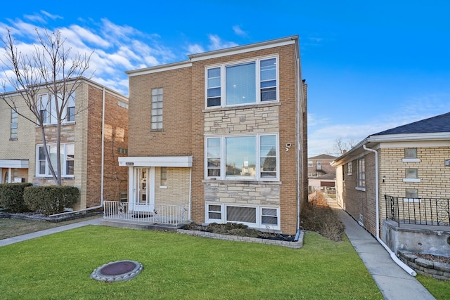 view of front of house featuring stone siding, brick siding, and a front lawn