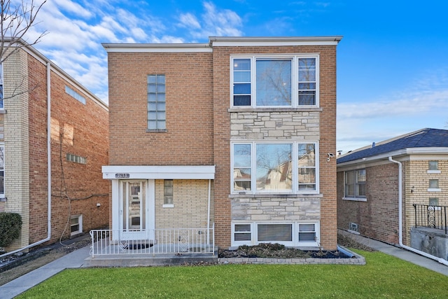 view of front facade with stone siding, brick siding, and a front lawn