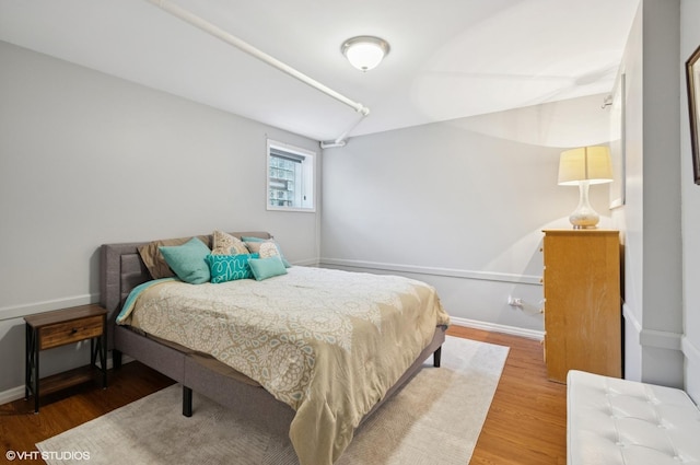 bedroom with lofted ceiling, baseboards, and wood finished floors