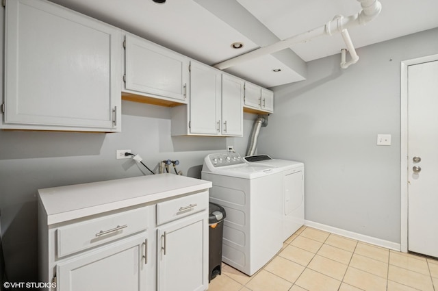 laundry area with light tile patterned floors, separate washer and dryer, cabinet space, and baseboards