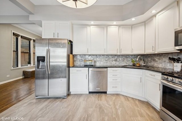 kitchen with stainless steel appliances, white cabinetry, a sink, and decorative backsplash