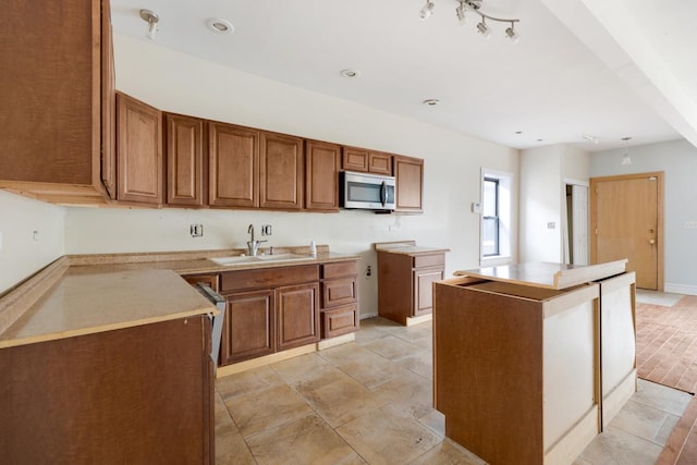 kitchen with a kitchen island, stainless steel microwave, brown cabinets, and a sink