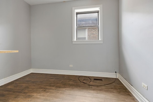 unfurnished room with baseboards, visible vents, and wood finished floors