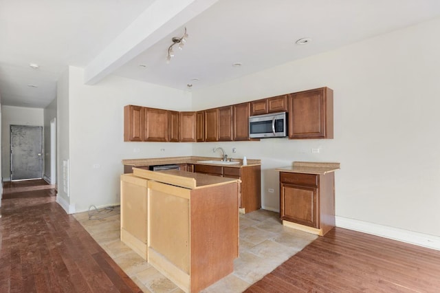 kitchen featuring light wood-type flooring, a center island, stainless steel microwave, and a sink