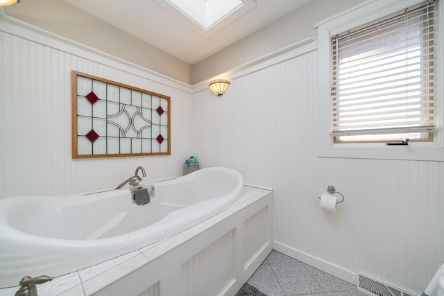 bathroom with a skylight, visible vents, and baseboards