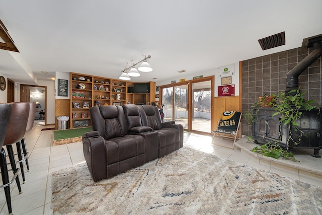 tiled living area featuring a wood stove and visible vents