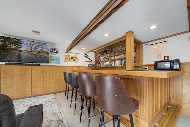 bar with a wainscoted wall, visible vents, black microwave, bar, and tile patterned floors