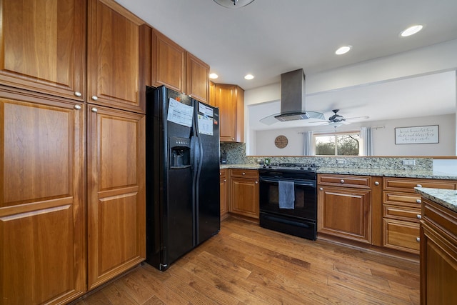 kitchen with black appliances, light wood-style flooring, island exhaust hood, and brown cabinets