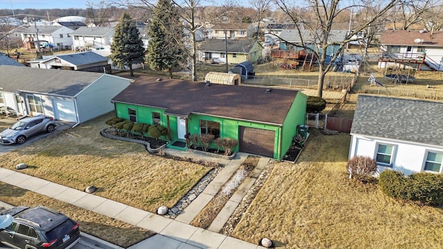 view of front of home with an attached garage, fence, a residential view, driveway, and a front lawn