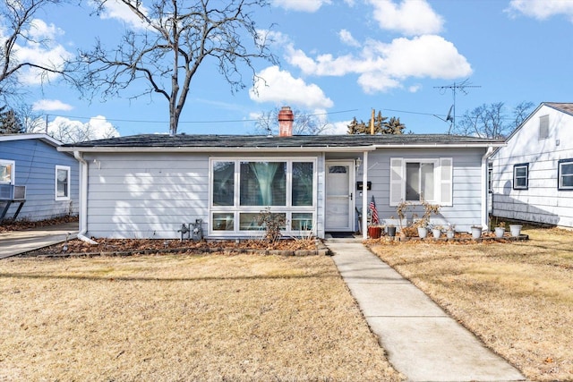 ranch-style home with a chimney and a front lawn