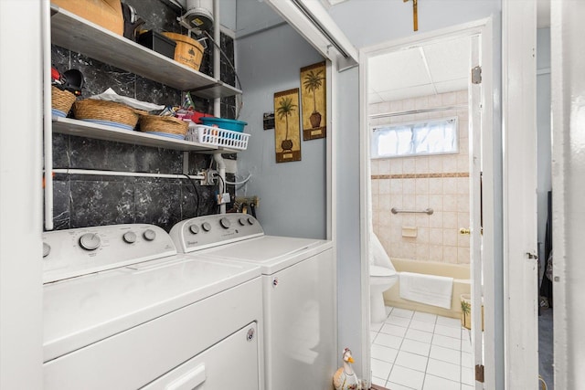 clothes washing area featuring laundry area, light tile patterned flooring, and washer and clothes dryer