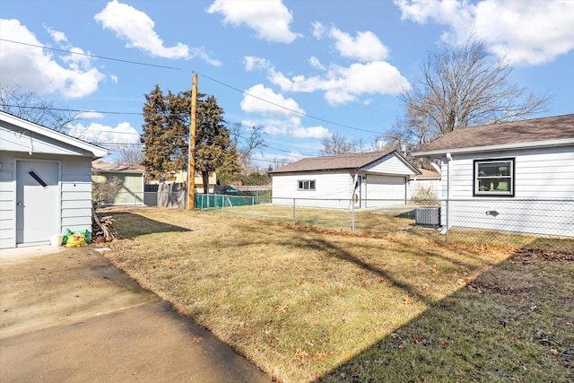 view of yard with cooling unit, fence, a detached garage, and an outdoor structure