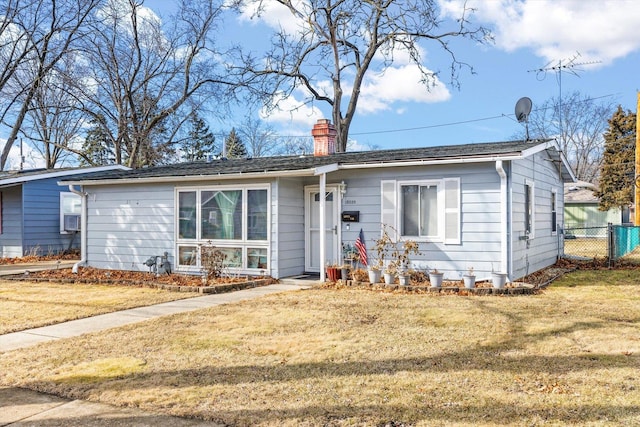 view of front of house with fence, a chimney, and a front lawn