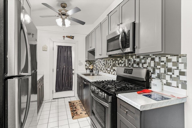 kitchen with tasteful backsplash, appliances with stainless steel finishes, light countertops, gray cabinetry, and a sink