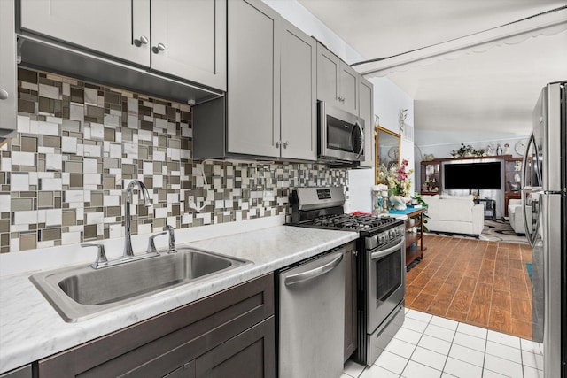 kitchen featuring a sink, open floor plan, light countertops, appliances with stainless steel finishes, and tasteful backsplash